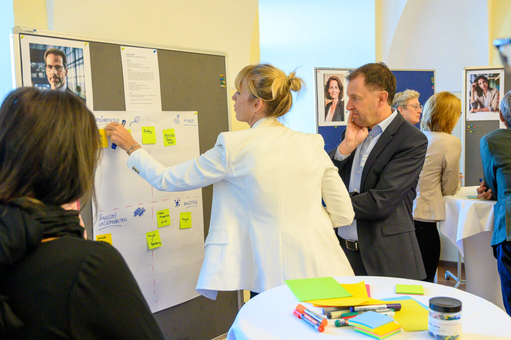 Teilnehmende arbeiten gemeinsam an einem Scrum-Board und priorisieren Aufgaben mit Haftnotizen. Das Bild symbolisiert die Einführung und Weiterentwicklung agiler Arbeitsweisen, die Moderation durch einen Scrum Master sowie die kontinuierliche Verbesserung von Prozessen und Zusammenarbeit in Scrum-Teams.